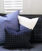 set of embroidered throw pillows in blue, black and whites on grey sofa