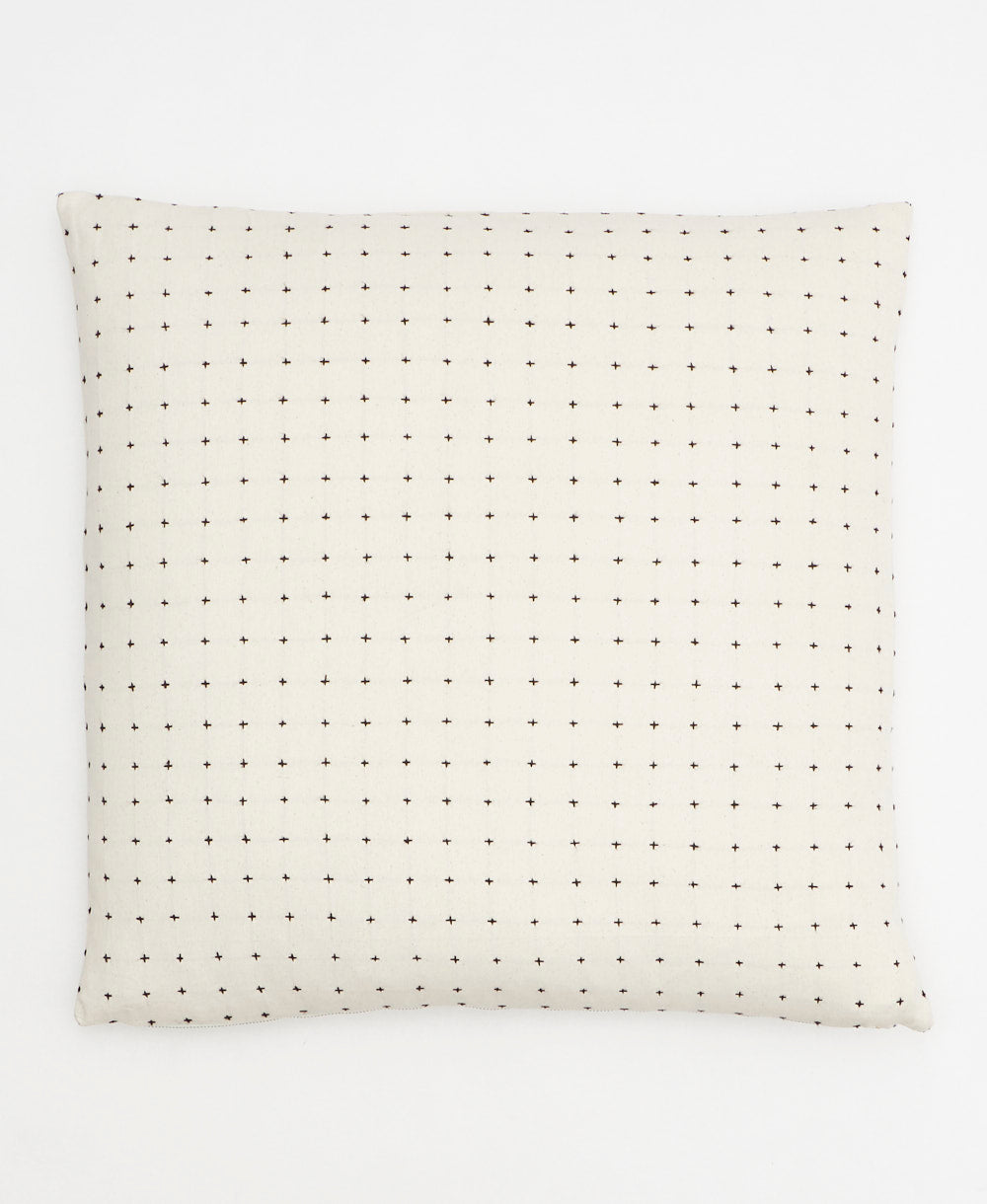 White pillow with black dot pattern on a white background