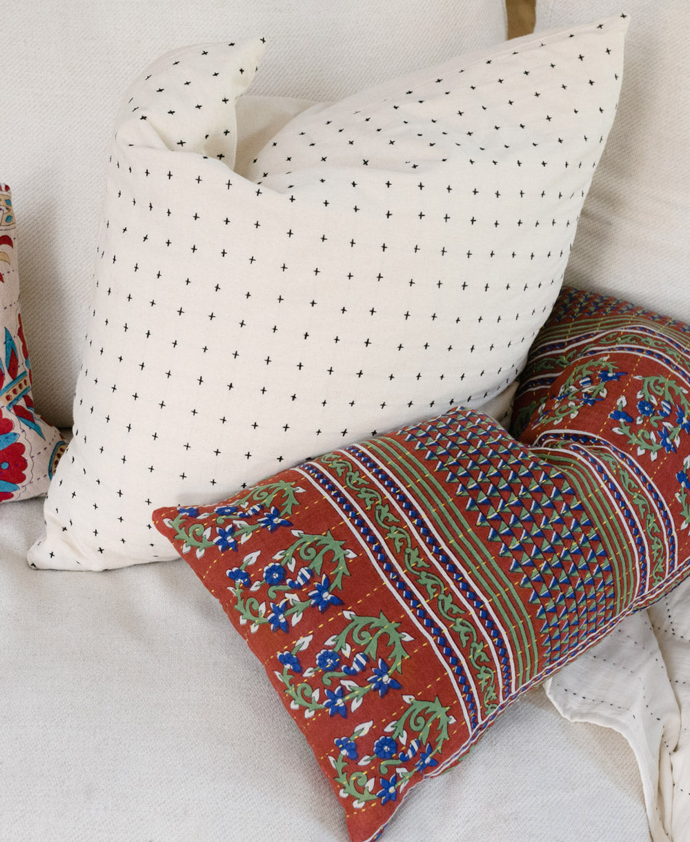 Decorative pillows with a polka dot pattern and a colorful embroidered design on a white sofa