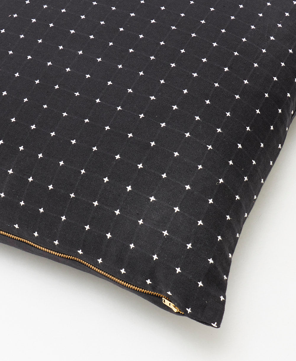 close up detail of black throw pillow with white tiny cross-stitches