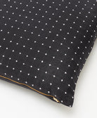 close up detail of black throw pillow with white tiny cross-stitches