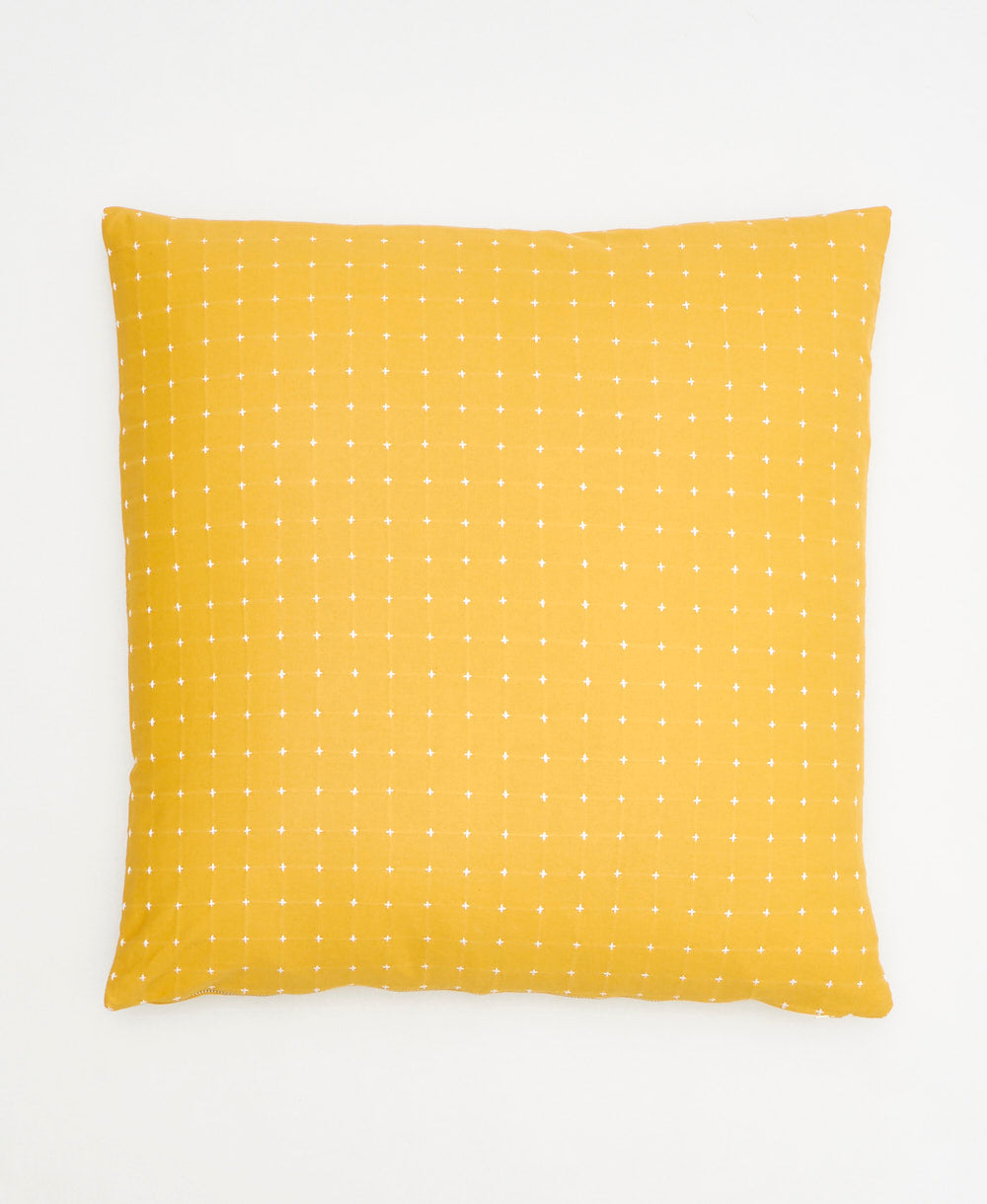 mustard yellow throw pillow with tiny white cross-stitch embroidery handmade in India