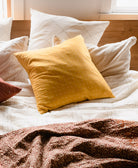 Yellow pillow on a bed with white and brown bedding
