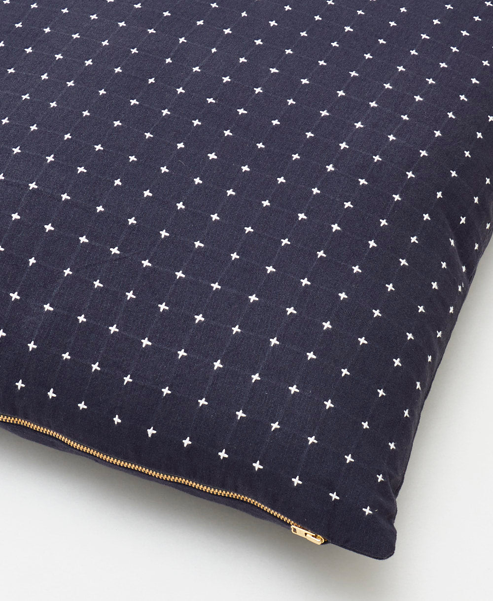 close up of navy cross-stitch throw pillow with brass tone zipper closure