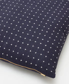 close up of navy cross-stitch throw pillow with brass tone zipper closure
