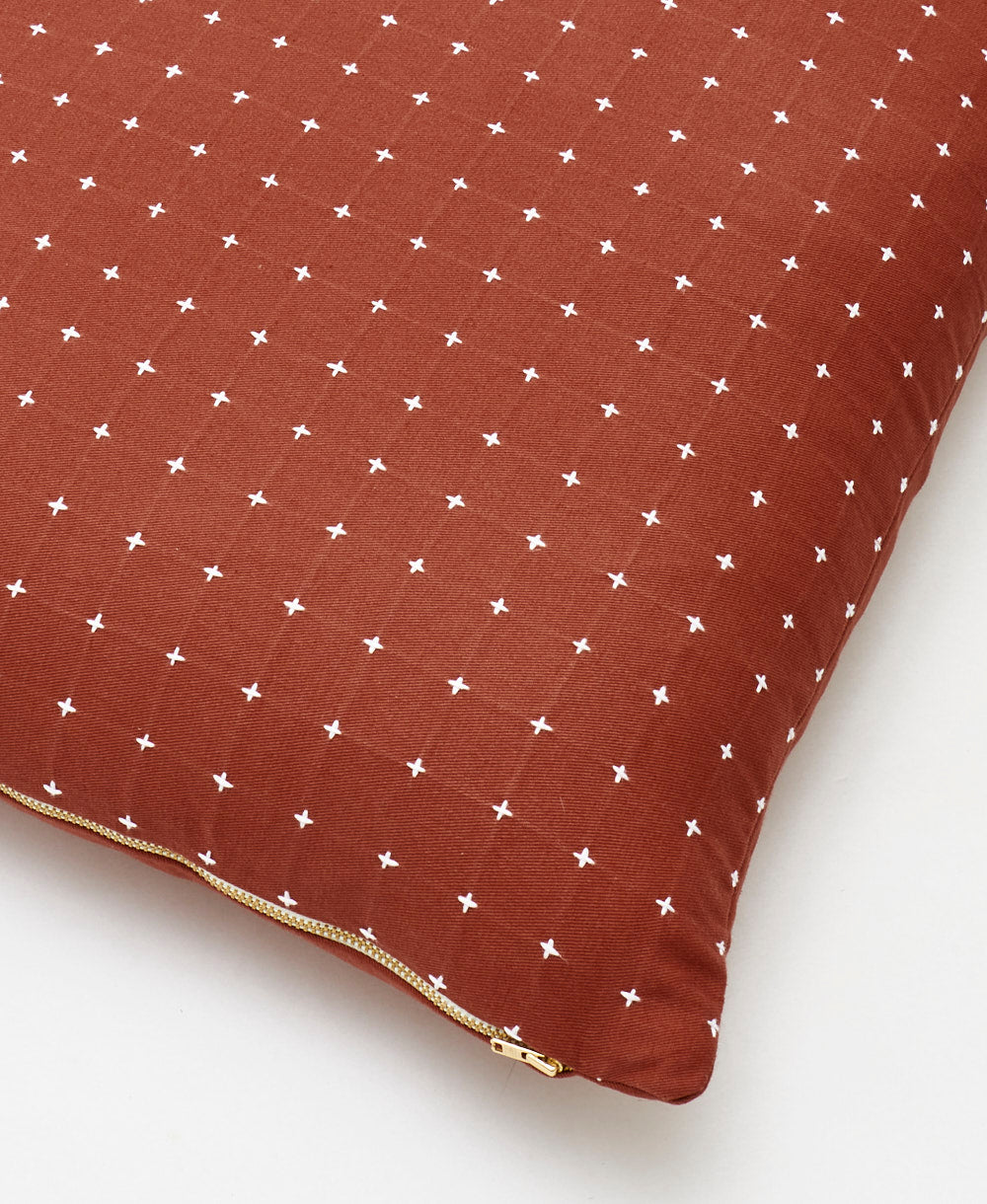 rust red throw pillow with tiny white cross-stitch embroidery and brass metal zipper closure