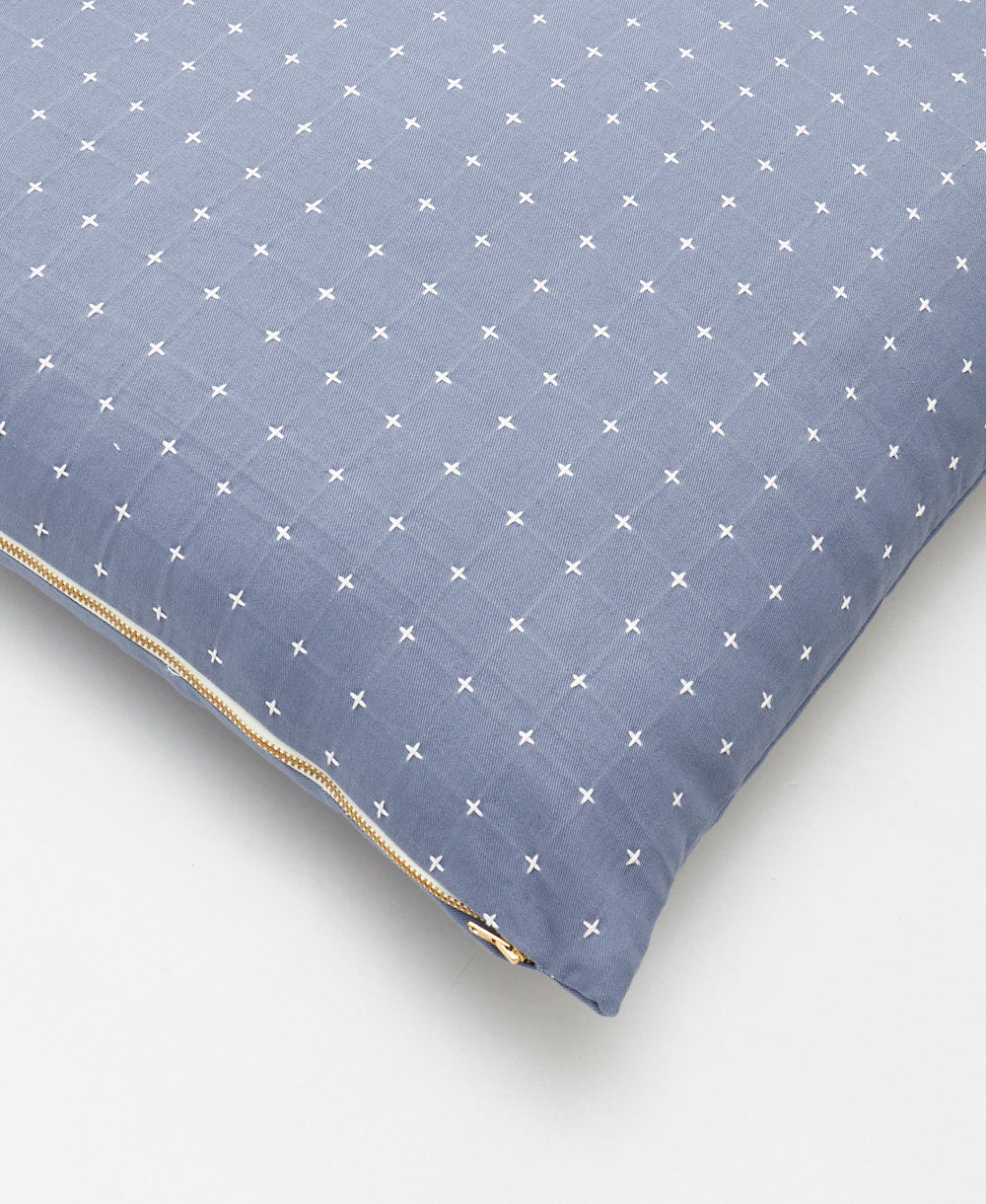 close up detail of slate blue throw pillow with tiny white cross-stitch design