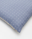 close up detail of slate blue throw pillow with tiny white cross-stitch design