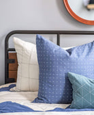 Close-up of slate blue pillows on a bed with a neutral background