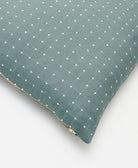 spruce green throw pillow with white cross-stitch embroidery and brass gold tone zipper