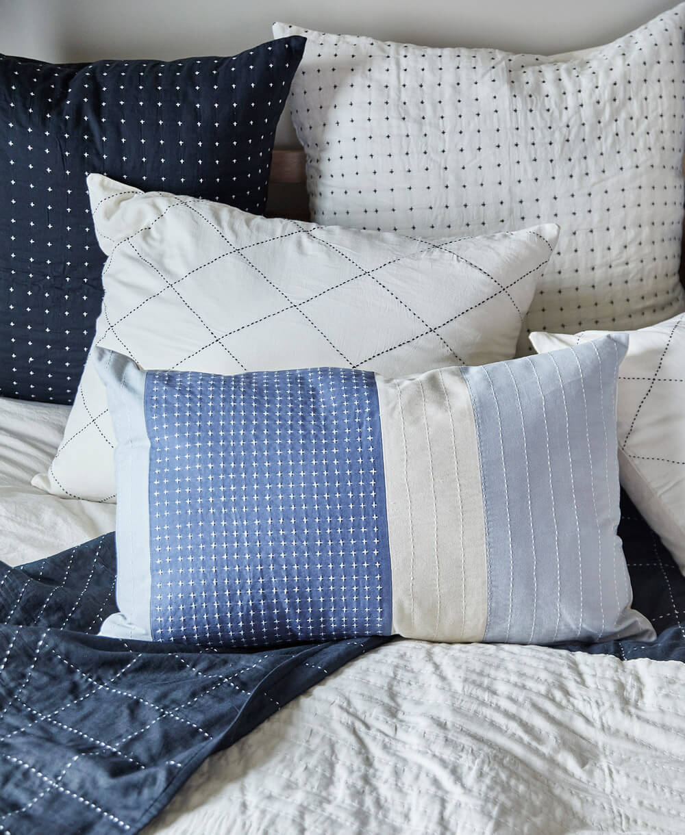 Collection of decorative pillows with blue, white, and patterned designs on a bed
