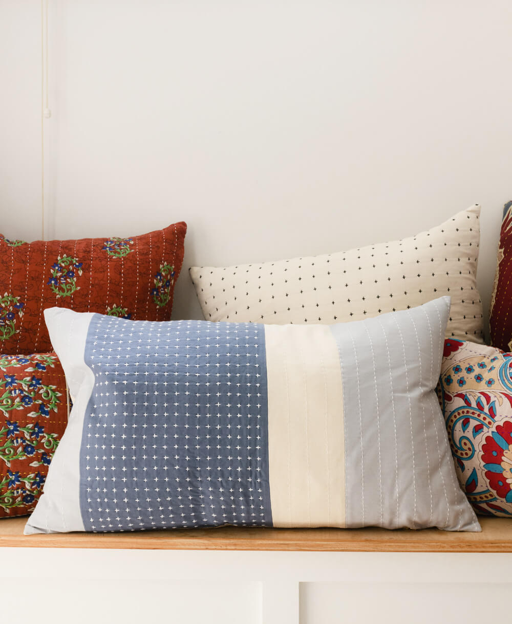 Colorful patterned pillows on a wooden bench with a neutral background