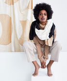 woman wearing eclipse long scarf loosely draped around her neck sitting on a white bench