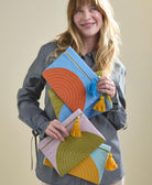 woman holding colorful pouch clutches in different bold colorblocking colorways