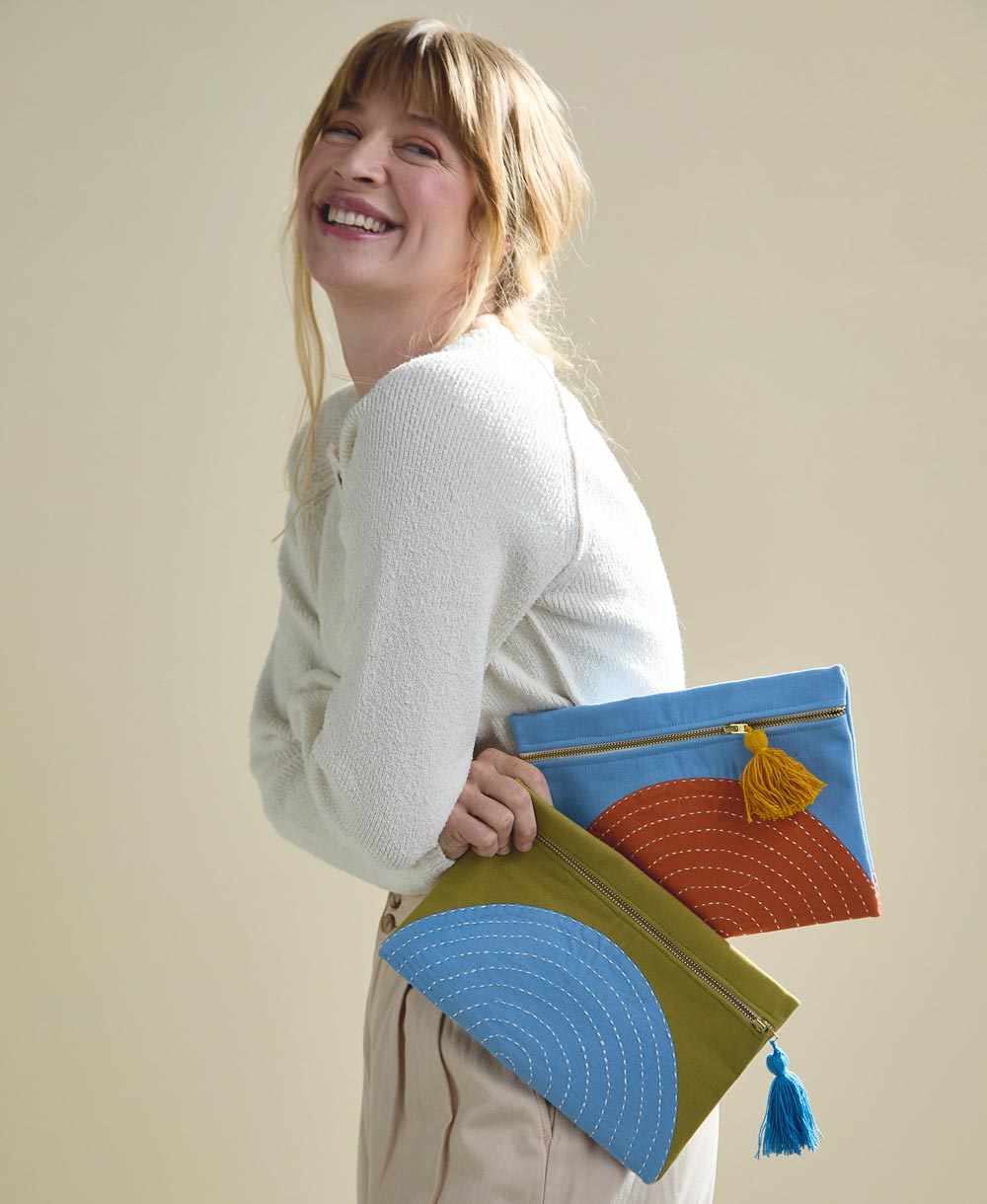 woman holding olive green and sky blue small pouch and a sky blue and orange pouch