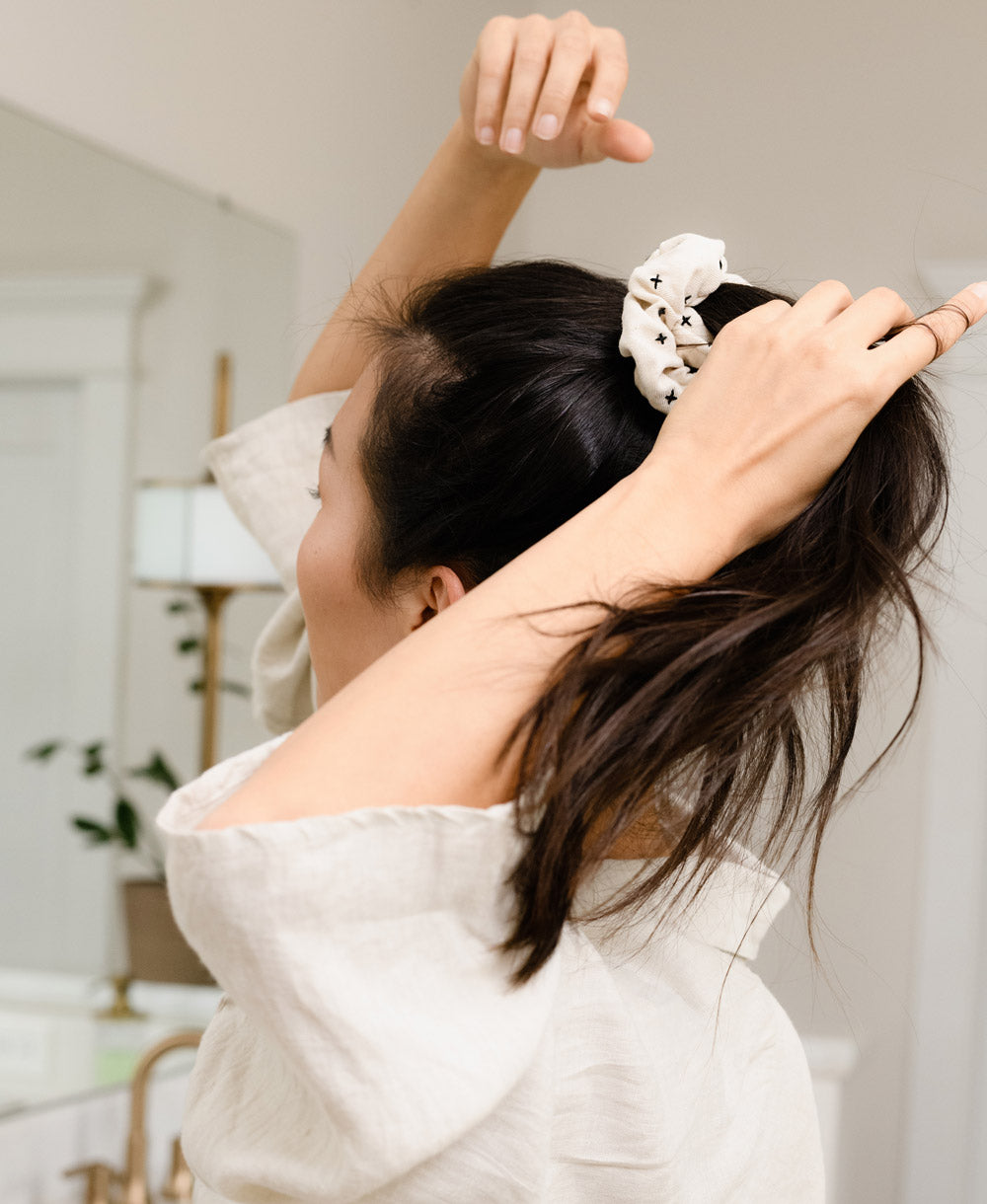 woman putting her hair into a ponytail with an organic cotton scrunchie