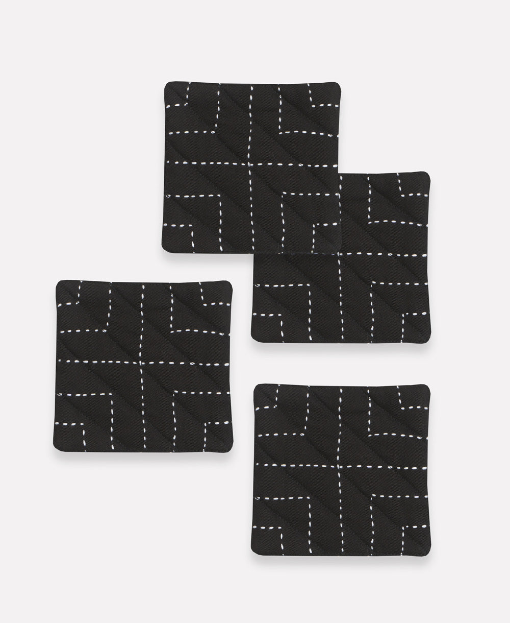 Set of four black coasters with white line patterns on a white background