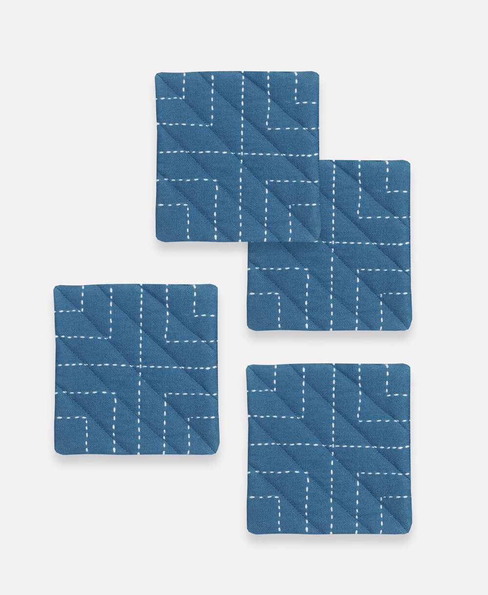 Set of four blue coasters with white line patterns on a white background