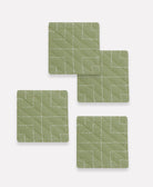 Set of four green quilted coasters with white stitching on a white background