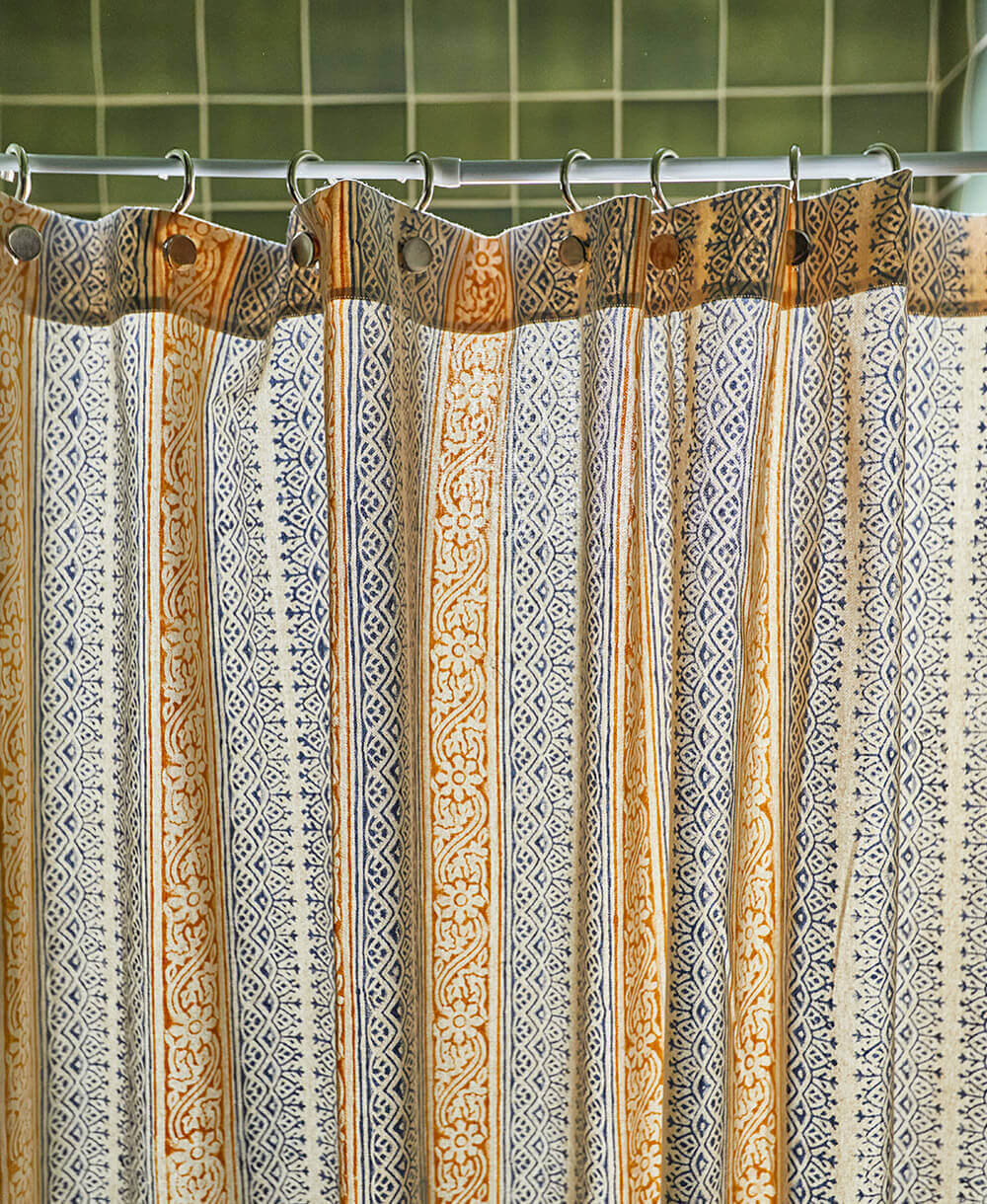 Patterned shower curtain with decorative hooks on a tiled bathroom wall