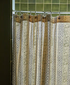Decorative shower curtain with intricate patterns and gold accents against a tiled bathroom wall.