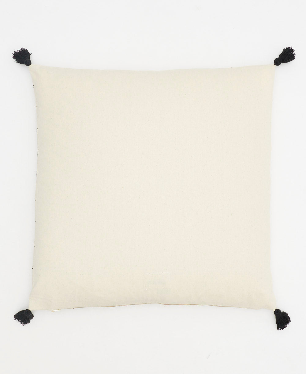 back of geometric stitch throw pillow in natural white with black tassels on the corner