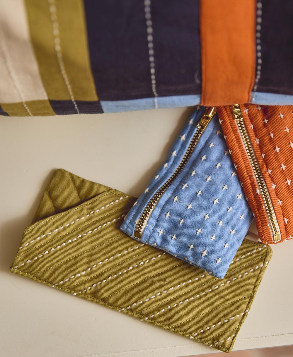 embroidered glasses case in green with coordinating blue and orange cross-stitch coin purses