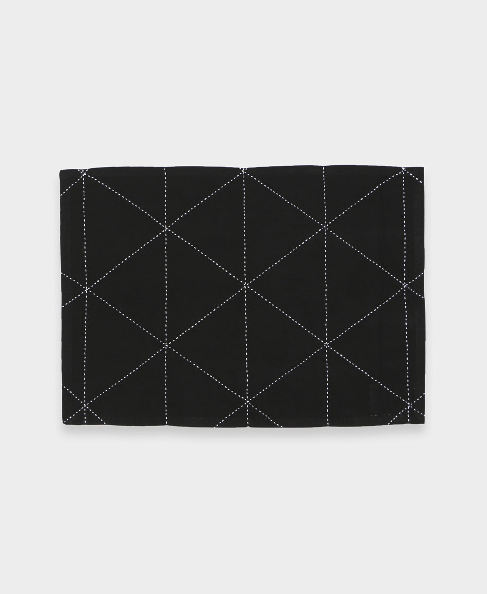 black cotton placemat with white hand-stitched embroidery