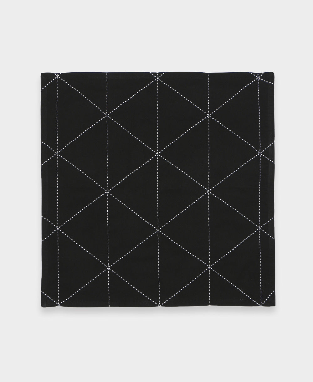 black cloth napkin with white geometric embroidered diamond pattern