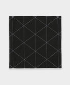 Black cotton napkin with white geometric stitching pattern on a light gray background