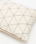 Cream-colored pillow with black geometric stitching and a gold zipper on a white background