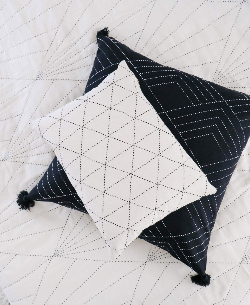 Two geometric-patterned pillows on a quilted surface