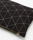 Black pillow with white geometric stitching and a gold zipper on a white background