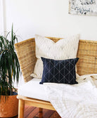 Wicker chair with decorative pillows and a plant in a room