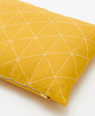 Yellow pillow with white geometric stitching on a white background