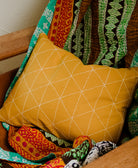 Colorful patterned fabric draped over a wooden chair with a yellow quilted pillow