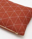 Red clutch bag with white geometric stitching on a white background