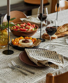 Dining table set with wine, cheese, and fruit platter on a patterned tablecloth