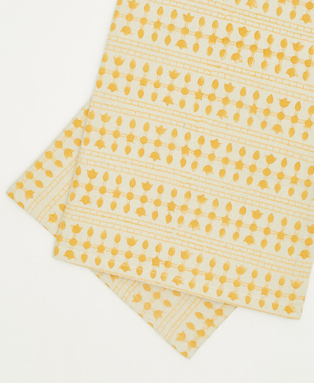 Two yellow patterned cloth napkins stacked on a white background