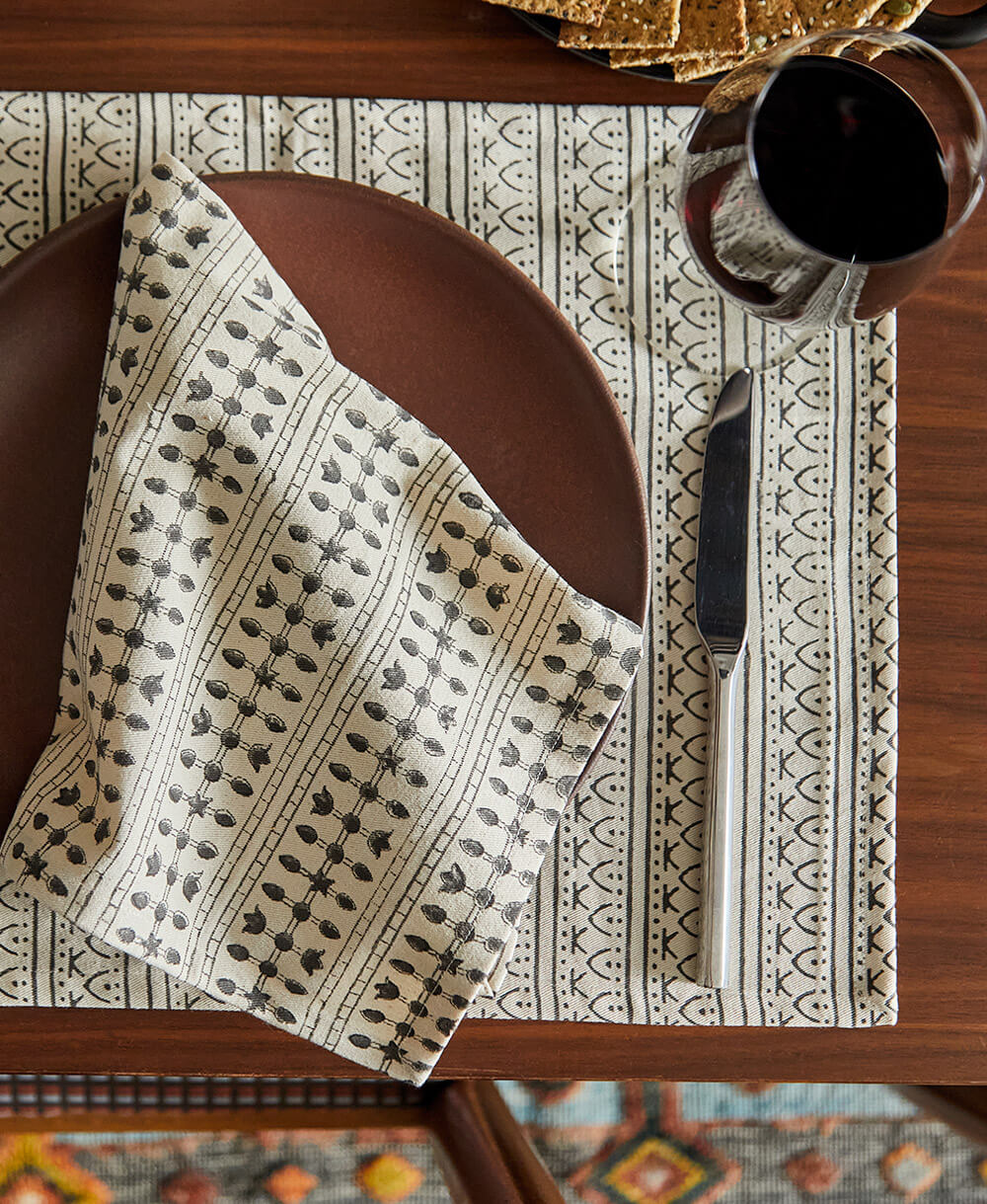 Patterned tablecloth with a napkin, plate, and cutlery on a wooden table