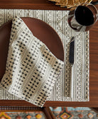 Patterned tablecloth with a napkin, plate, and cutlery on a wooden table
