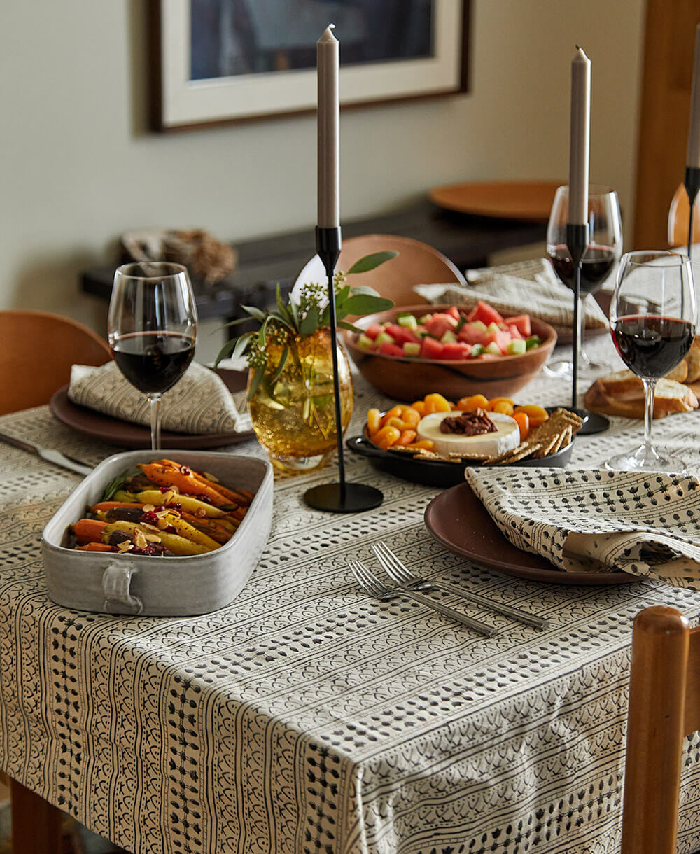 Dining table set with a patterned tablecloth, food, and wine glasses