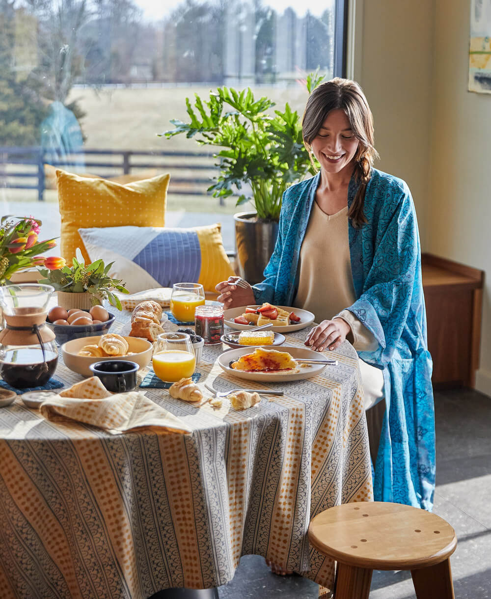 Woman sitting at a dining table with a breakfast spread, smiling