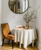 round cafe table in corner with grid print tablecloth on table with vase with centerpiece