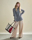 woman carrying block print grid mini tote bag by the handle in black and white