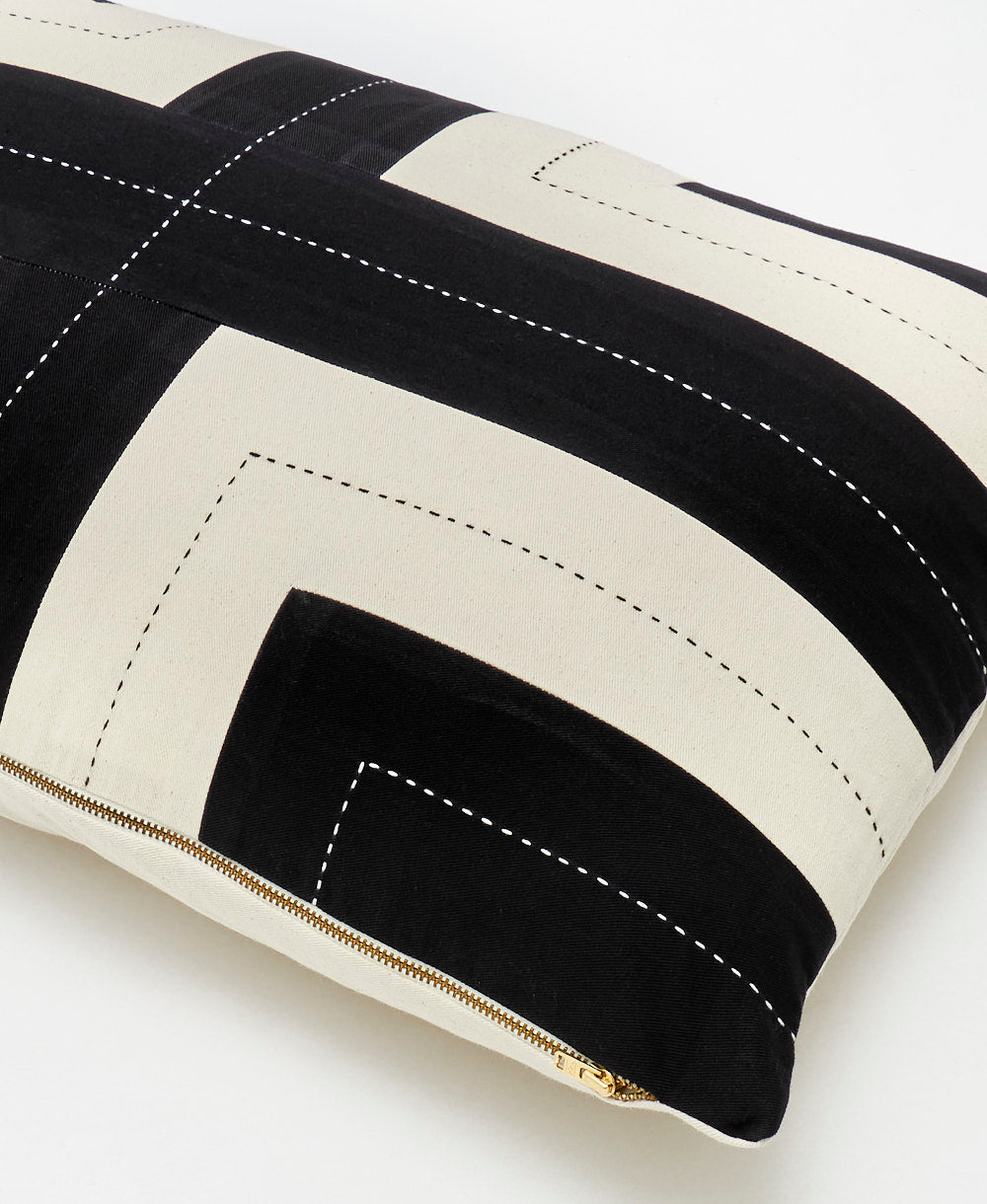 Black and white striped pillow with visible stitching on a light background