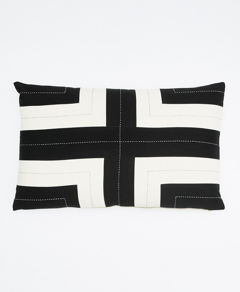 Black and white striped pillow with a cross design on a white background