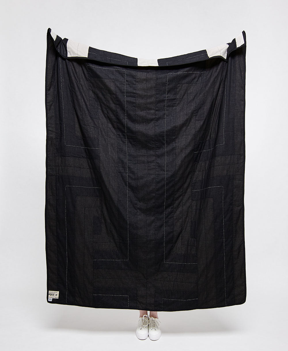 Black quilt draped over a person on a white background