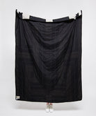 Black quilt draped over a person on a white background