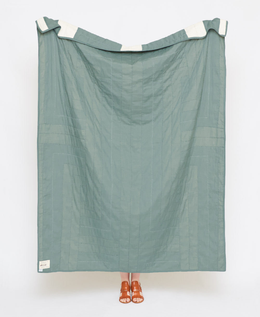 Green fabric draped over a white frame on a white background